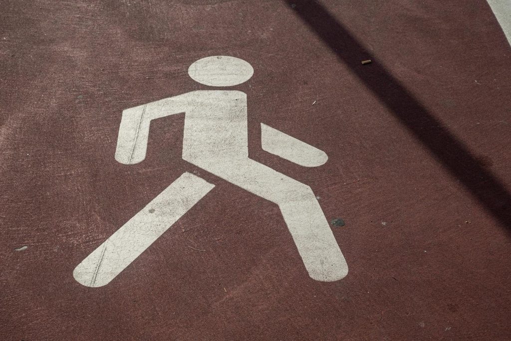 Close-up of a pedestrian symbol painted on a concrete sidewalk in urban setting.
